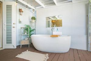 a white bathroom with a tub and a mirror at Casa Loba Suite 1 with an outdoor tub in Rincon +22 photos