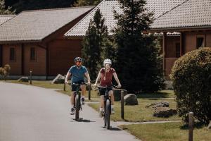 Un hombre y una mujer andan en bicicleta por una carretera en Chaletdorf ZellerSee, en Maishofen