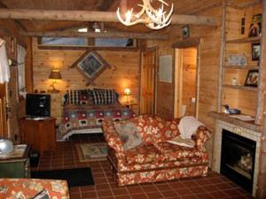 een woonkamer met een bank en een bed bij All Season Romantic One-Room Cabin on Moody Pond, in Upstate New York in Saranac Lake