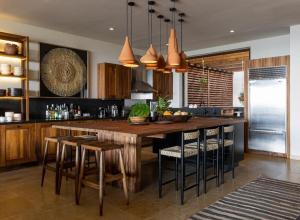 a kitchen with a large wooden island with bar stools at Los Veneros Punta de Mita - Pacific Tower in Punta Mita