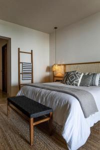 a bedroom with a large bed with a bench next to it at Los Veneros Punta de Mita - Pacific Tower in Punta Mita