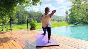 a man standing on a yoga mat next to a pool at Villa Samas in Galle