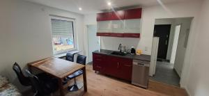una cucina con una scrivania e un tavolo e una cucina con mobili rossi di Ferienwohnung Langwasser a Norimberga Altre 2 foto