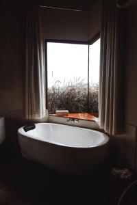 une grande baignoire dans une salle de bain avec une fenêtre dans l'établissement Bangalô de Pedras, à São Thomé das Letras