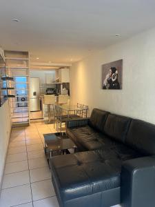 un salon avec un canapé en cuir et une cuisine dans l'établissement Chez Theo, à Marseille