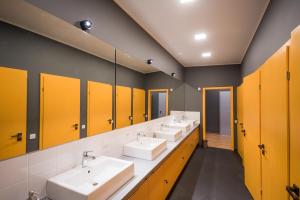 uma casa de banho com quatro lavatórios e portas amarelas em Friday Hostel em Odessa