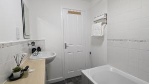 a white bathroom with a sink and a toilet and a tub at Modern Four Bedroom House near Attractions, Stadium, Town Centre, Parks and Lake - Sky n Netflix - Convenient Transport in Burnley +29 photos