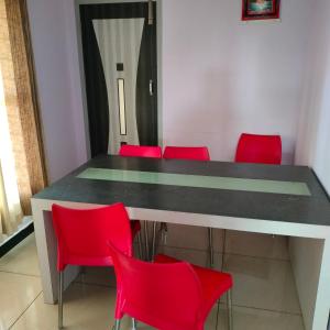 a table with red chairs in a room at Wild Nest Kotagiri in Kotagiri