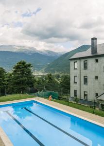 a swimming pool with a view of a building and mountains at Casa Los Altos de Santiago in Villanúa