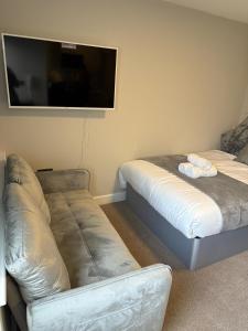 a room with two beds and a couch and a flat screen tv at Modern Studio London Near Hospital in Thornton Heath