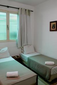 two beds in a room with a window at Pousada Vó Irene in Itacuruçá