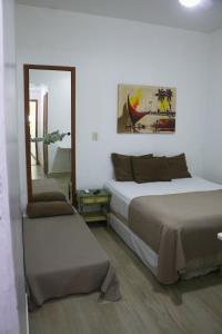 a bedroom with two beds and a mirror at Pousada Vó Irene in Itacuruçá