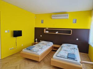 two beds in a room with a yellow wall at Penzion BránaBeskyd in Frýdlant nad Ostravicí +42 photos