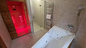 baño con bañera y puerta roja en Apartment ABAKUS with jacuzzi & sauna, en Demänovská Dolina