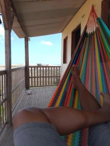 uma pessoa deitada numa rede de descanso num deque em Pousada degamix em Barroquinha