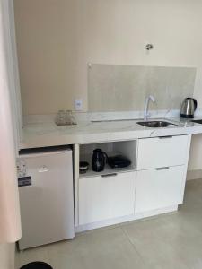 a white kitchen with a sink and a counter at Apartamento solteiro sinop 9 in Sinop