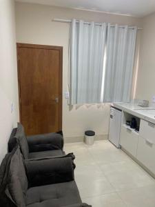 a living room with a chair and a kitchen at Apartamento solteiro sinop 9 in Sinop