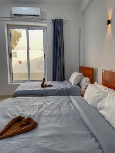 Cette chambre comprend deux lits et une fenêtre avec une serviette. dans l'établissement Villa Al Rabia, à Louxor