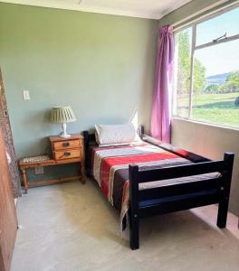 a bedroom with a bed and a window at Field's End in Howick