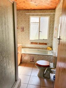 a bathroom with a toilet and a tub and a window at Field's End in Howick