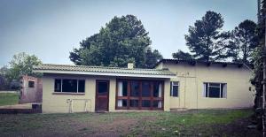 a small white house with wooden doors in a yard at Field's End in Howick