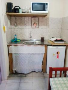 une petite cuisine avec un évier et un micro-ondes dans l'établissement Chalé em Penedo - Linda Vista Condomínio, à Itatiaia