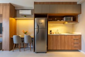 a kitchen with a refrigerator and a table with chairs at Upper West Perdizes by Xtay - Nubank Parque a 500m - antigo Allianz Parque - estúdio moderno com cozinha e vista da cidade in São Paulo