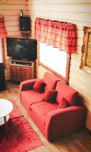 un soggiorno con un divano rosso e una TV di Luksushuvila louhosjärven rannalla a Isokyrö