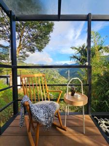 a wooden chair and a table on a balcony at Banaue Glass Cabins in Banaue
