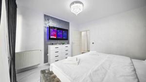 a white bedroom with a bed and a tv on the wall at RT Luxury Royal Residence in Braşov