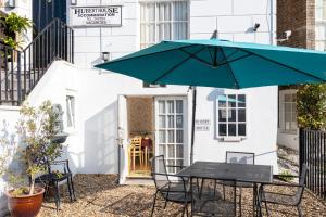 a table and chairs with an umbrella in front of a building at Hubert House in Dover