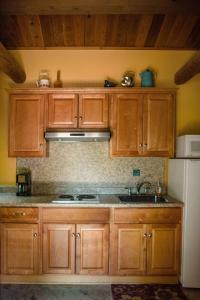a kitchen with wooden cabinets and a sink and a refrigerator at HONEYSUCKLE - Rustic cabin for 2 in Oak Creek Canyon in Indian Gardens