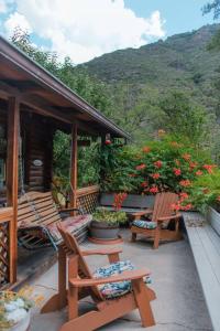 a porch with two wooden chairs and flowers at HONEYSUCKLE - Rustic cabin for 2 in Oak Creek Canyon in Indian Gardens