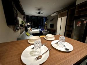 a table with two white plates and silverware on it at Scarletz suites klcc Twin Tower by ESD in Kuala Lumpur