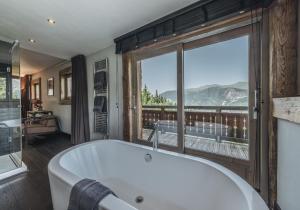 une baignoire dans une salle de bain avec une grande fenêtre dans l'établissement Chalet Artic - 5 bedrooms - Bed&Breakfast - Courchevel 1550, à Courchevel
