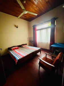 a bedroom with a bed and a chair and a window at Peaceful Haven Cozy Retreat in Nugegoda