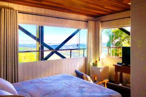 a bedroom with a bed and a large window at VELINN Pousada Pedras e Sonhos in Monte Verde