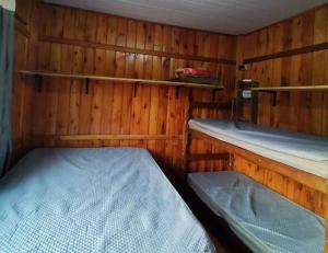 a small room with two beds and wooden walls at Hospedaje Vildumar in Pichilemu