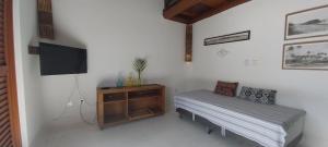 a bedroom with a bed and a tv and a table at Aloha Residence I in Praia do Forte
