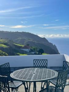 ein Tisch und Stühle auf einem Balkon mit Blick auf den Ozean in der Unterkunft Ocean Retreat in Fajã da Ovelha