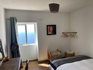 Schlafzimmer mit einem Bett, einem Fenster und einem Tisch in der Unterkunft Ocean Retreat in Fajã da Ovelha