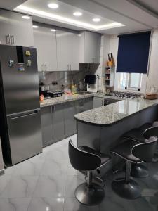 a kitchen with a counter with chairs and a refrigerator at Appartement Mdiq in M'diq
