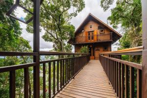 a wooden bridge leading to a cabin in the woods at VELINN Pousada Pedras e Sonhos in Monte Verde