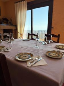 einen Tisch mit Tellern und Weingläsern darauf in der Unterkunft Hotel Restaurante Atalaya in Comares