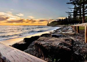 a beach with a rock wall and the ocean at 3 Moffat Beach Holiday House in Caloundra