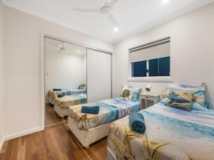 a bedroom with two beds and a mirror at 3 Moffat Beach Holiday House in Caloundra +18 photos