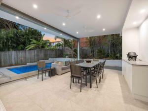a patio with a table and chairs and a pool at 3 Moffat Beach Holiday House in Caloundra