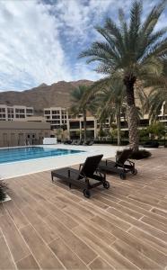Una piscina con dos tumbonas junto a una palmera. en Muscat Bay ! - Stay Where Ocean, Mountains and Luxury Come Together !, en Mascate