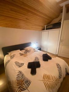 een slaapkamer met een groot wit bed met bladeren erop bij Cocon cosy au cœur des Pyrénées in Campan