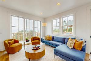 a living room with a blue couch and chairs and windows at Pacific Perch in Depoe Bay